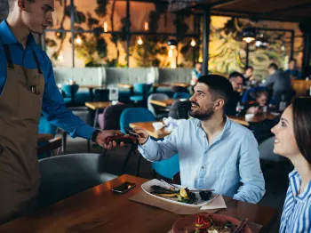 Restaurant server providing table service to customers at a local restaurant