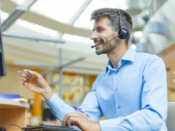 Professional customer support representative assisting a user by phone and computer