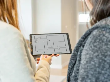 Professional reviewing home project plans on a tablet with a client