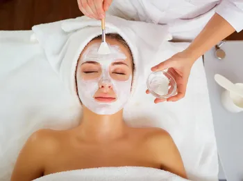 Esthetician applying a facial mask during a professional spa treatment