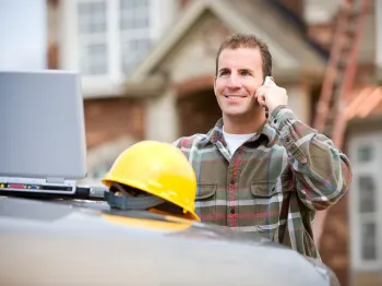 General contractor speaking with a client by phone outside a residential property