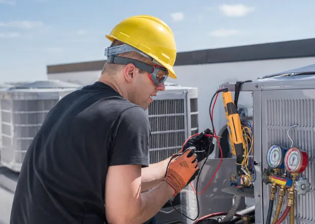 HVAC technician repairing an outdoor air conditioning unit