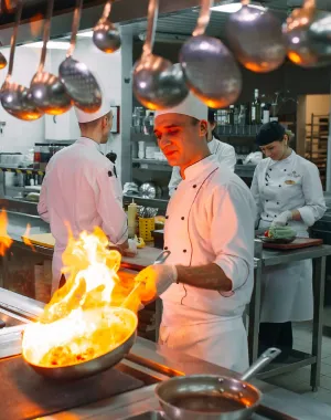 Professional chef preparing a flambé dish in a restaurant kitchen