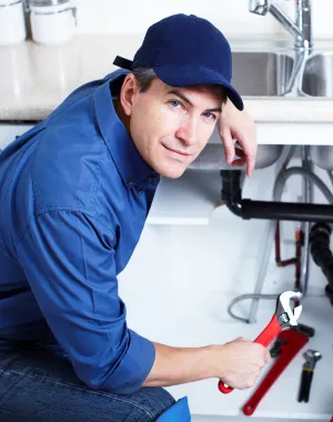 Professional plumber repairing pipes beneath a kitchen sink